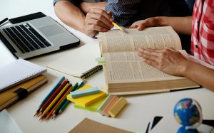 Education concept. Students studying and brainstorming campus concept. Close up of students discussing their subject on books textbooks and writing to notebook. Seclective focus.